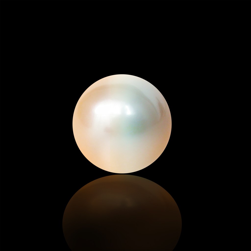 A single lustrous pearl resting on a reflective surface against a black background.