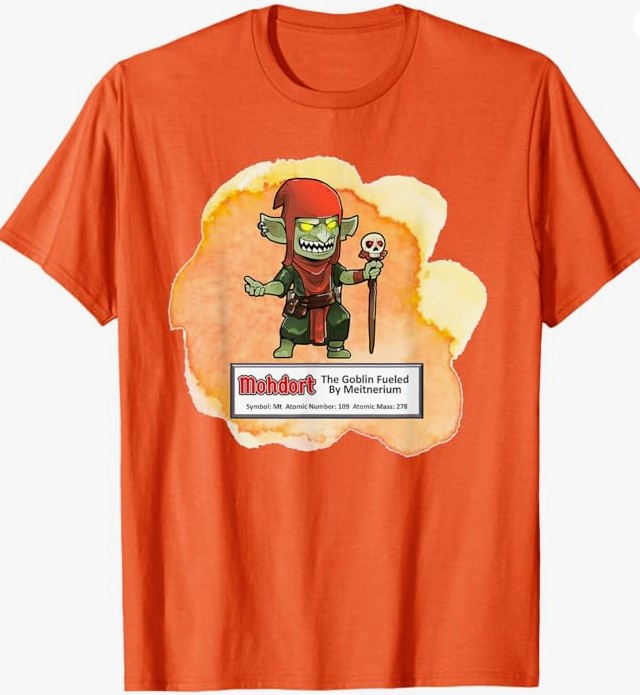 An orange t-shirt featuring a cartoon goblin named 'Mohdort' holding a skull, with a label that includes the text 'The Goblin Fueled By Metinierium' and scientific details like atomic number and mass.