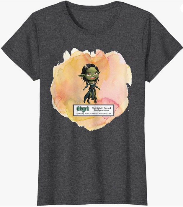 A dark gray t-shirt featuring a cartoon goblin character standing on a colorful watercolor background with a label that reads 'Otyrjt The Goblin Fueled by Oganesson'.
